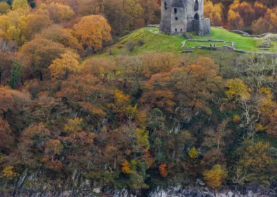 An elevated view of the round stone tower of Dolbadarn Castle overlooking Llyn Peris and the Llanberis Pass.
