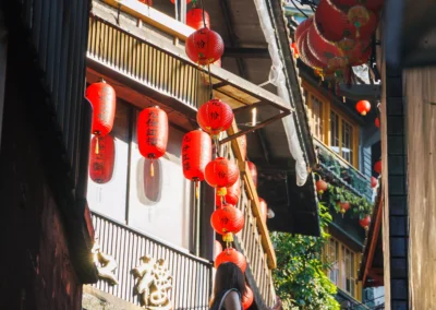 Amei Teahouse staircase in Jiufen with red lanterns, ivy walls and small bronze statues at the base