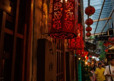 Close-up of an ornate cut-out red lantern glowing at dusk in Jiufen with a blue sky background