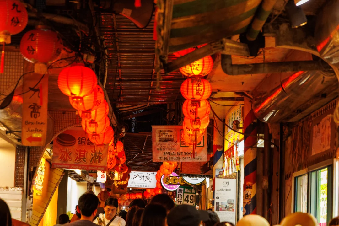 Jiufen covered alley packed with evening visitors below glowing orange and red lanterns