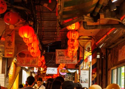 Jiufen covered alley packed with evening visitors below glowing orange and red lanterns