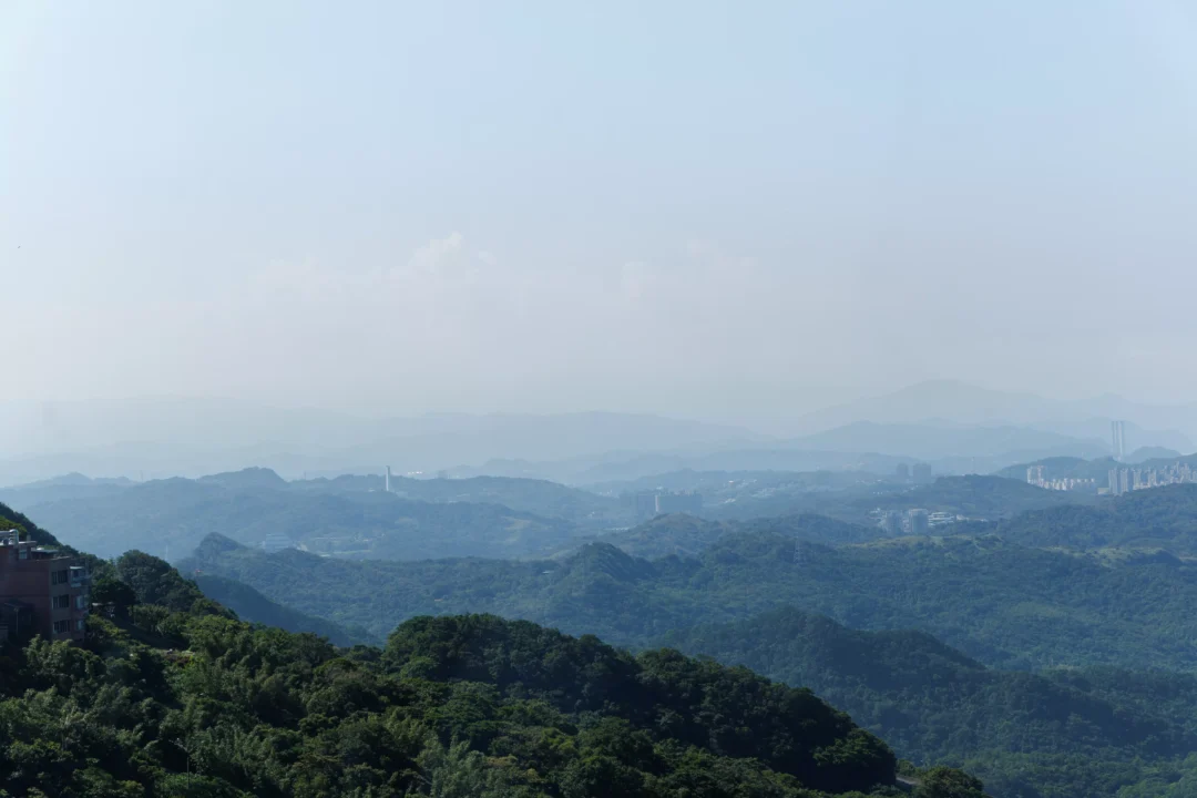 View from Jiufen hilltop over orange temple rooftops, forested hills and the blue Pacific coast