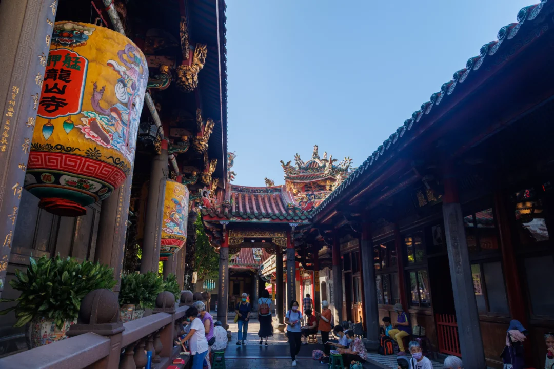 Longshan Temple courtyard with painted lanterns and worshippers among ornate wooden buildings