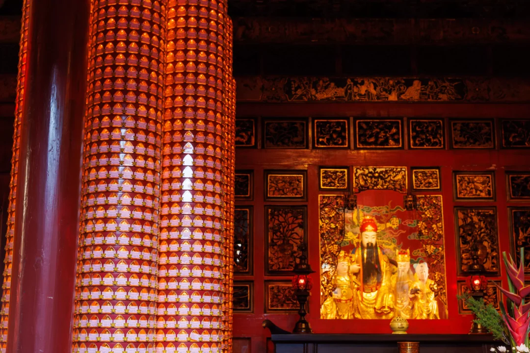 Glowing red interior of Longshan Temple with rows of prayer tablets and a golden deity shrine