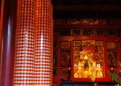 Glowing red interior of Longshan Temple with rows of prayer tablets and a golden deity shrine
