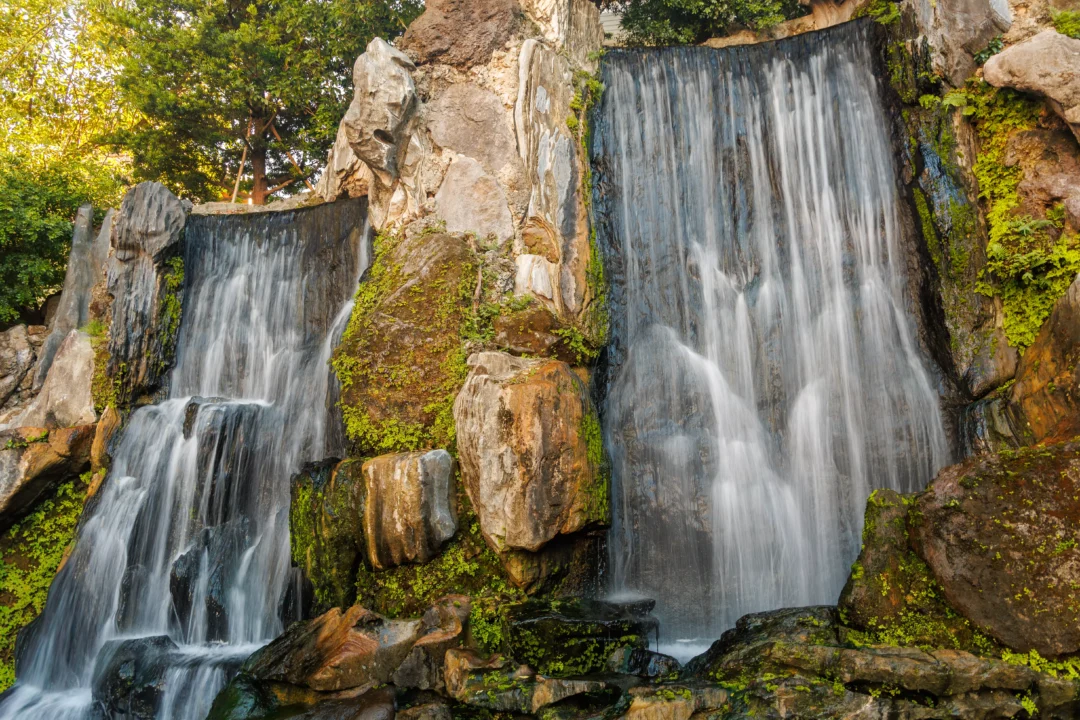 Twin waterfalls in Longshan Temple gardens with golden light catching the surrounding trees