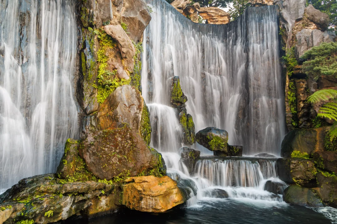 Long exposure photograph of a cascading waterfall with mossy rocks in Longshan Temple gardens