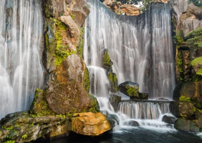 Long exposure photograph of a cascading waterfall with mossy rocks in Longshan Temple gardens