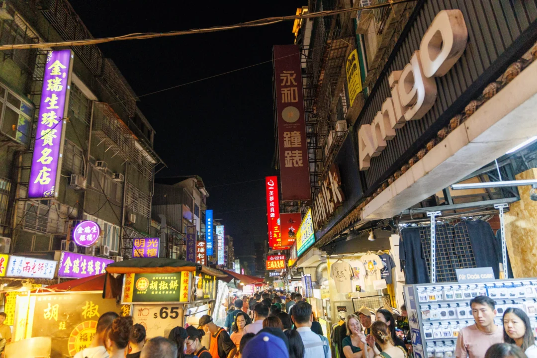 Raohe Street Night Market looking down the main street lined with neon signs and food stalls at night