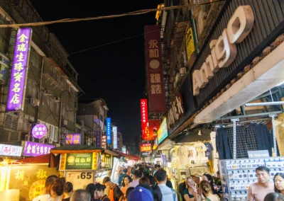 Raohe Street Night Market looking down the main street lined with neon signs and food stalls at night
