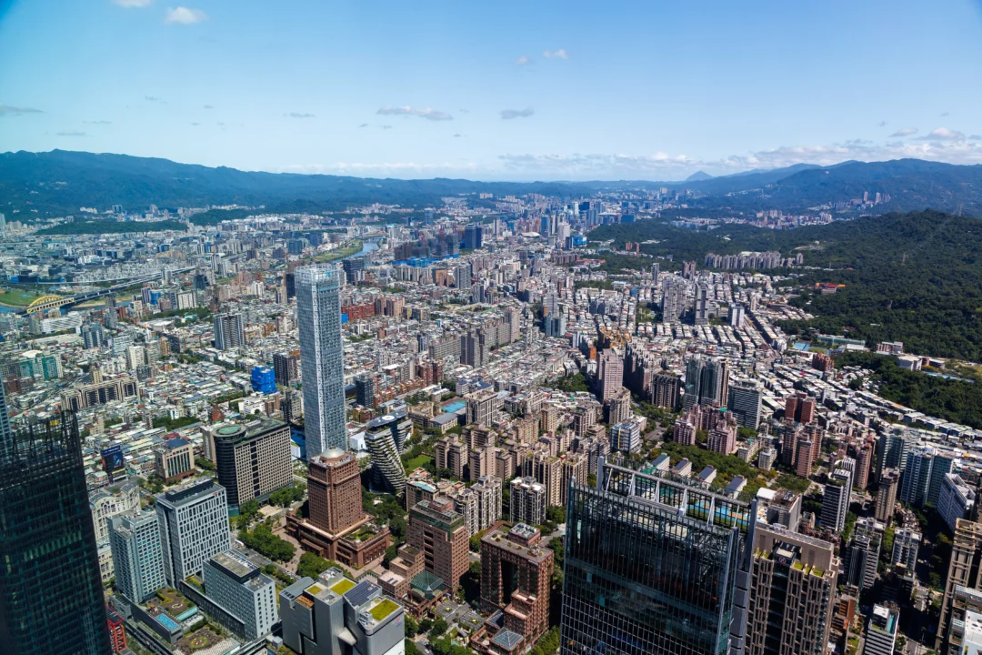 Wide aerial panorama of Taipei from Taipei 101 with mountains and dramatic clouds on the horizon