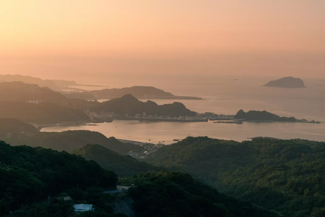 Golden sunset over Taiwan's northeast coast seen from Jiufen hillside with layered headlands and Keelung Island