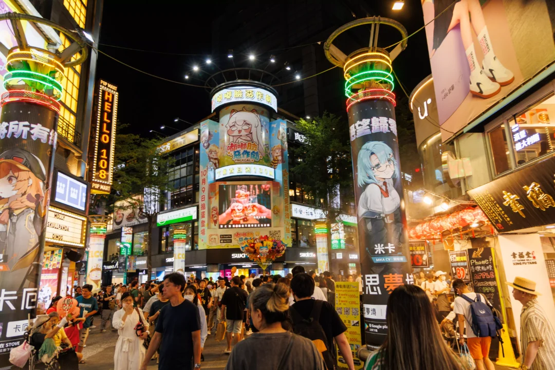 Ximending at night from a slightly wider angle showing the neon-lit junction and busy street below