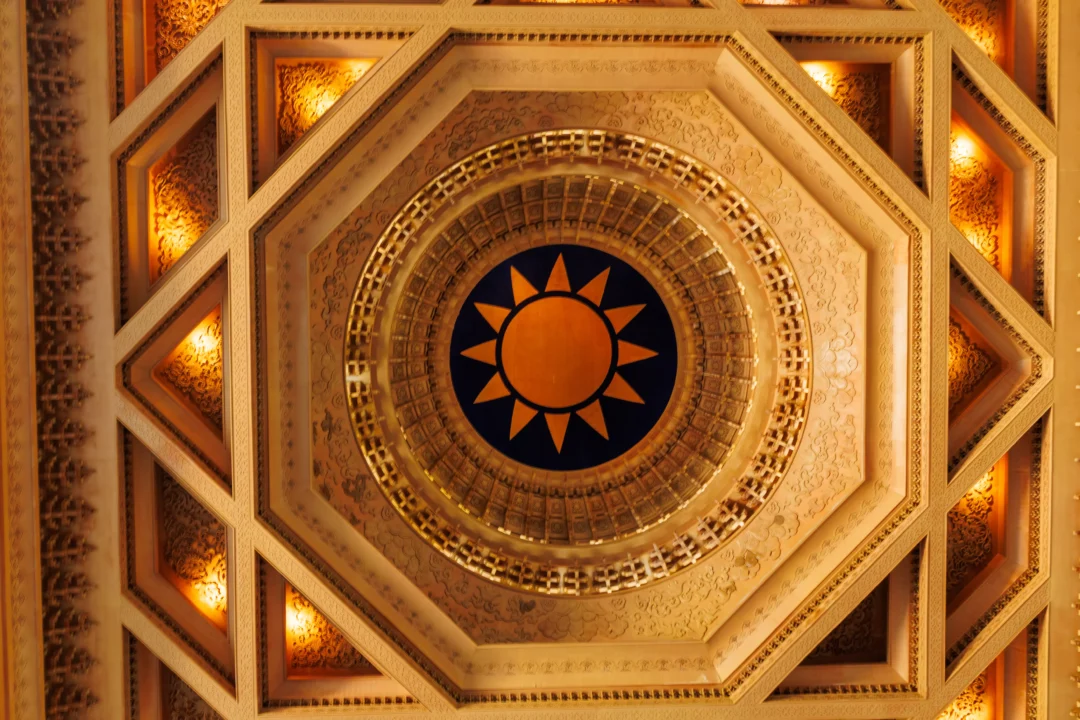 Ornate octagonal ceiling inside Chiang Kai-shek Memorial Hall with blue and orange sun motif and warm amber lighting