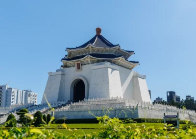 Chiang Kai-shek Memorial Hall rising above manicured hedges and gardens, viewed from low angle with blue sky