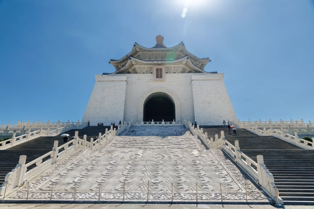 Looking up the carved marble staircase of Chiang Kai-shek Memorial Hall towards the entrance arch with sun flare above