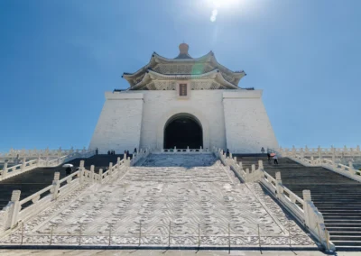 Looking up the carved marble staircase of Chiang Kai-shek Memorial Hall toward the entrance arch with sun flare above