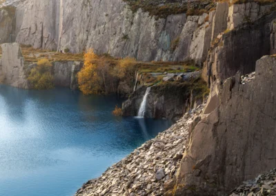 A view through the stone doorway of a roofless quarry ruin looking out at the hazy Snowdonia mountains.