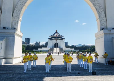 Group of performers in yellow uniforms playing drums framed through a white arch of the Liberty Square gate, with Chiang Kai-shek Memorial Hall visible in the distance