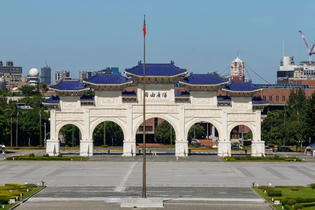 The Liberty Square ceremonial gate in Taipei with central flagpole and Taipei city skyline behind under blue sky