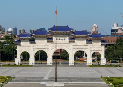 The Liberty Square ceremonial gate in Taipei with central flagpole and Taipei city skyline behind under blue sky