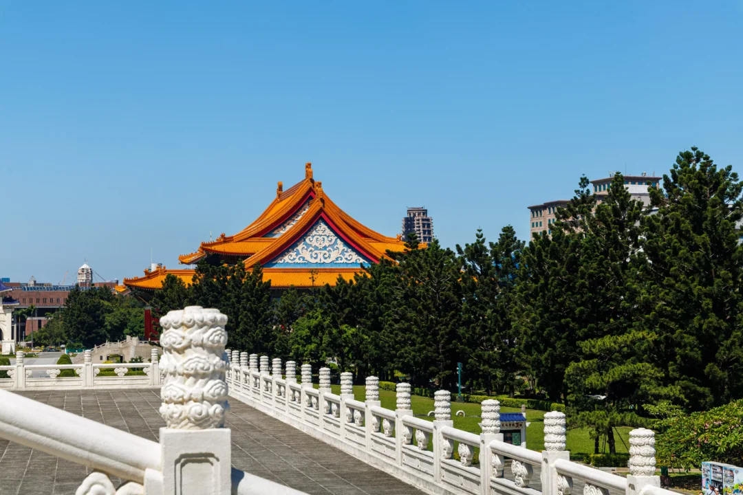 Stone carved balustrade post in the foreground with the orange roofline of the National Concert Hall visible above green trees