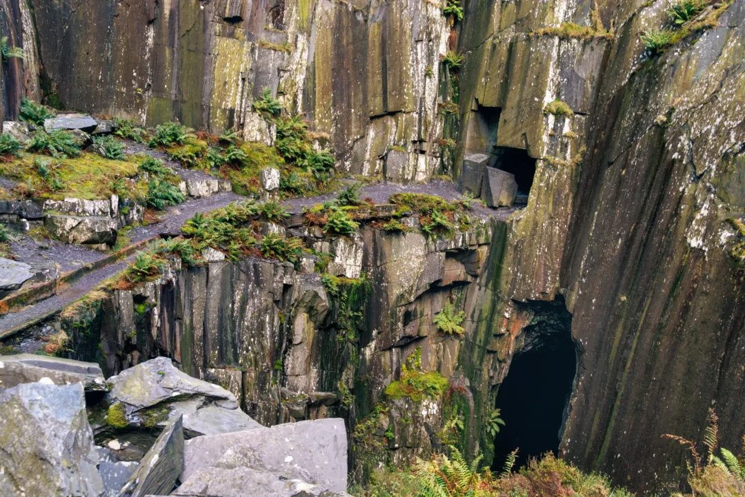 Terraced slate quarry benches with a deep blue-black pool at Dinorwig Quarry, Snowdonia, in autumn