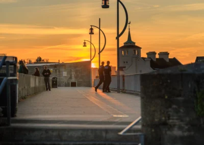 Two police officers walking along the raised coastal path by the Hot Walls during a rich, warm sunset.