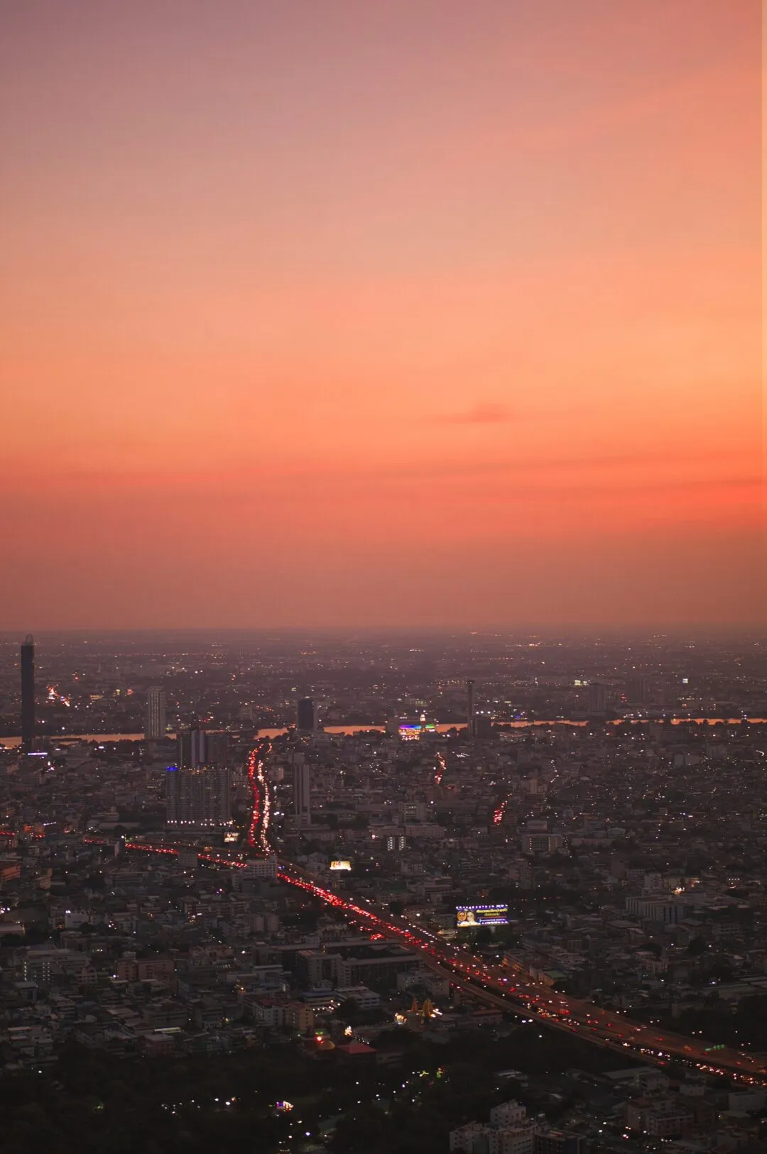 An elevated view over the Bangkok skyline at dusk beneath a full sky colour gradient.
