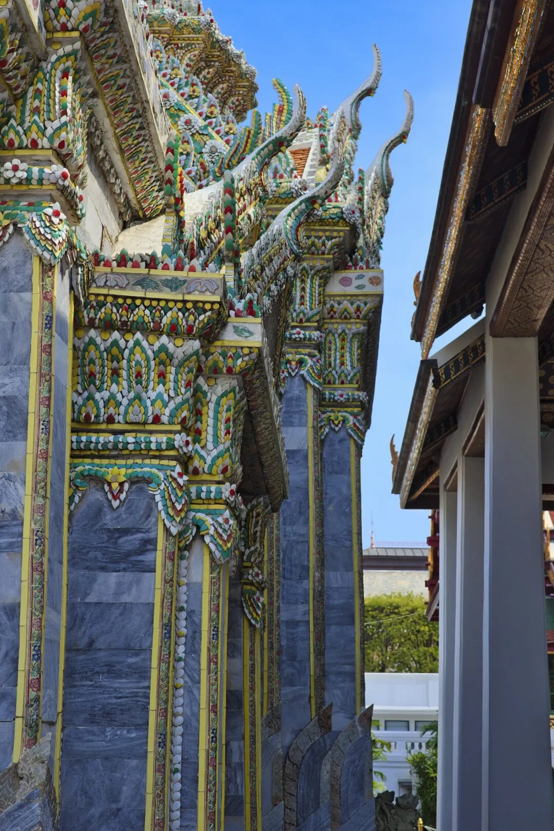 Blue marble-mosaic pillars and gilded eaves at a Bangkok temple complex.