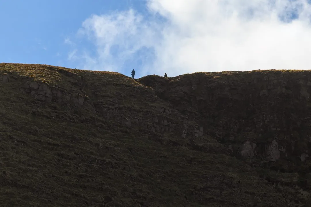 Hikers silhouette cliff edge, the Brecon Beacons, Wales