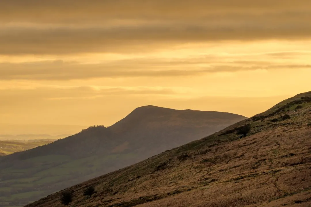 Isolated peak silhouette golden sky, the Brecon Beacons, Wales