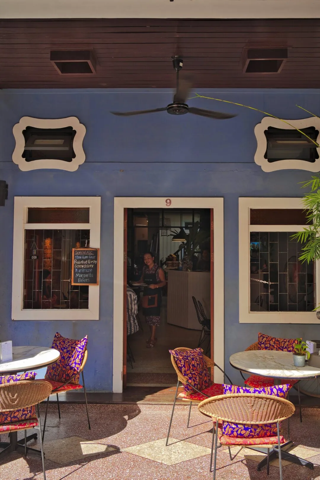 The interior of a heritage café in Phuket Old Town, with a ceiling fan and window light.