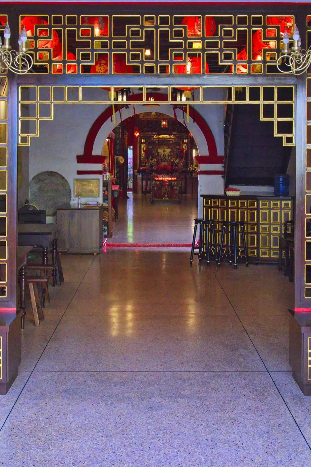 A corridor lined with red lanterns leading to a lit shrine interior in Phuket.