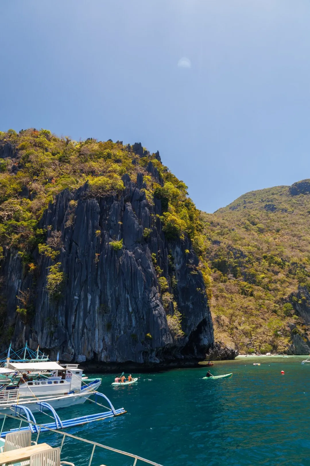 Dramatic karst pinnacle boats snorkelers El Nido