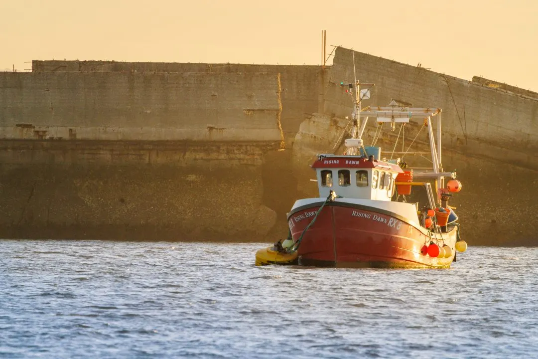 Fishing boat rising dawn sea wall, Eastney