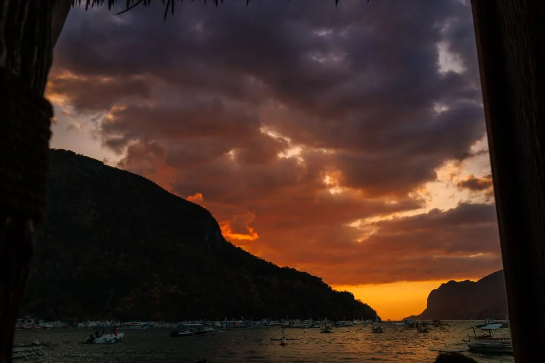 Framed sunset harbour thatched roof El Nido
