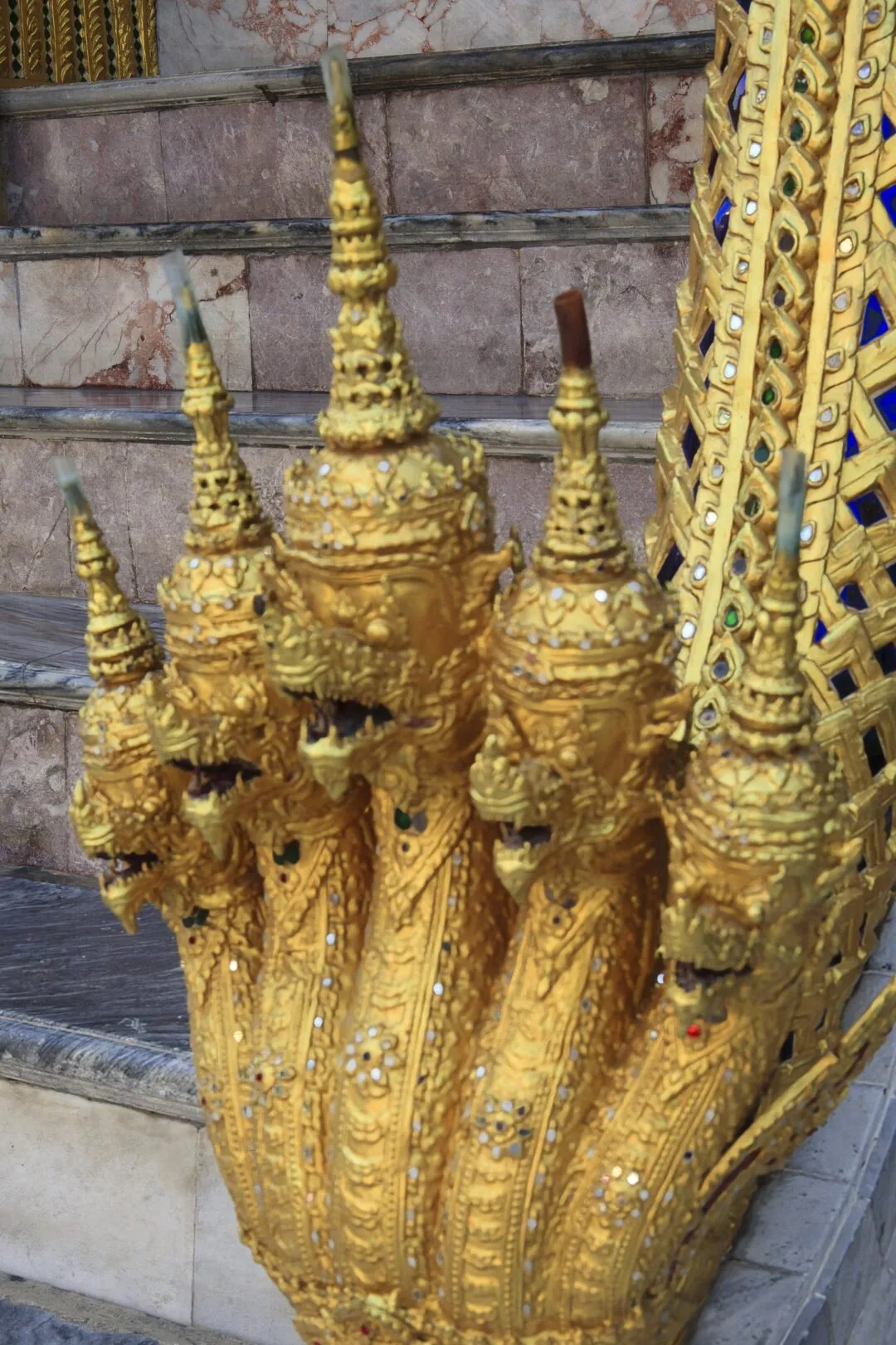 A close-up of an intricately gilded naga serpent balustrade ornament at a Bangkok temple.