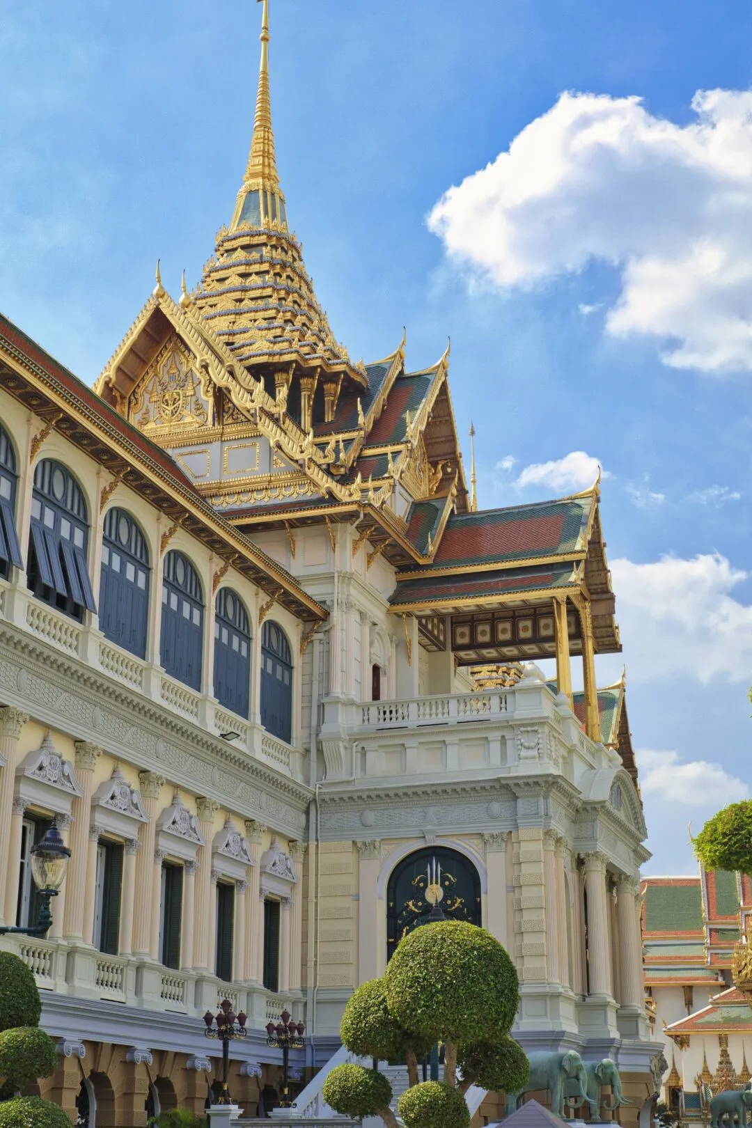 A dramatic upward angle on a gilded, multi-tiered temple spire in Bangkok.