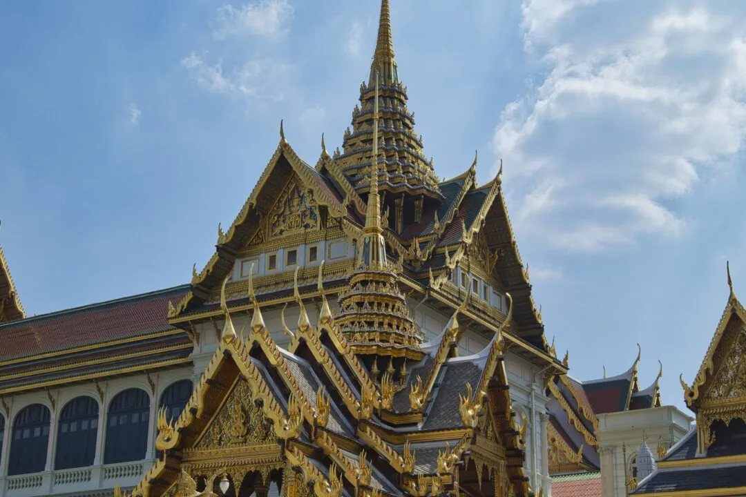 A dense, heavily gilded temple roof shot from a dramatic low angle in Bangkok.