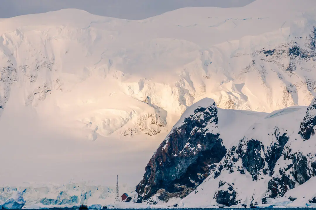 Golden late light breaking through cloud onto a dramatic snow-draped ridge on the Antarctic Peninsula