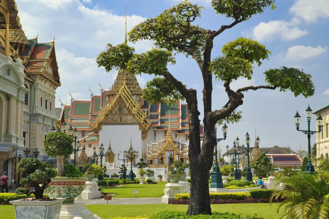 A golden-roofed pavilion seen across manicured formal gardens in Bangkok.