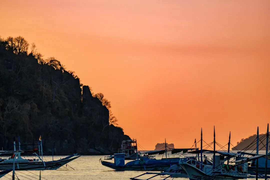 Gradient sunset mountain silhouette fishing boat El Nido