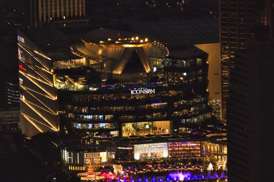 The illuminated ICONSIAM riverside complex at night in Bangkok, Thailand.