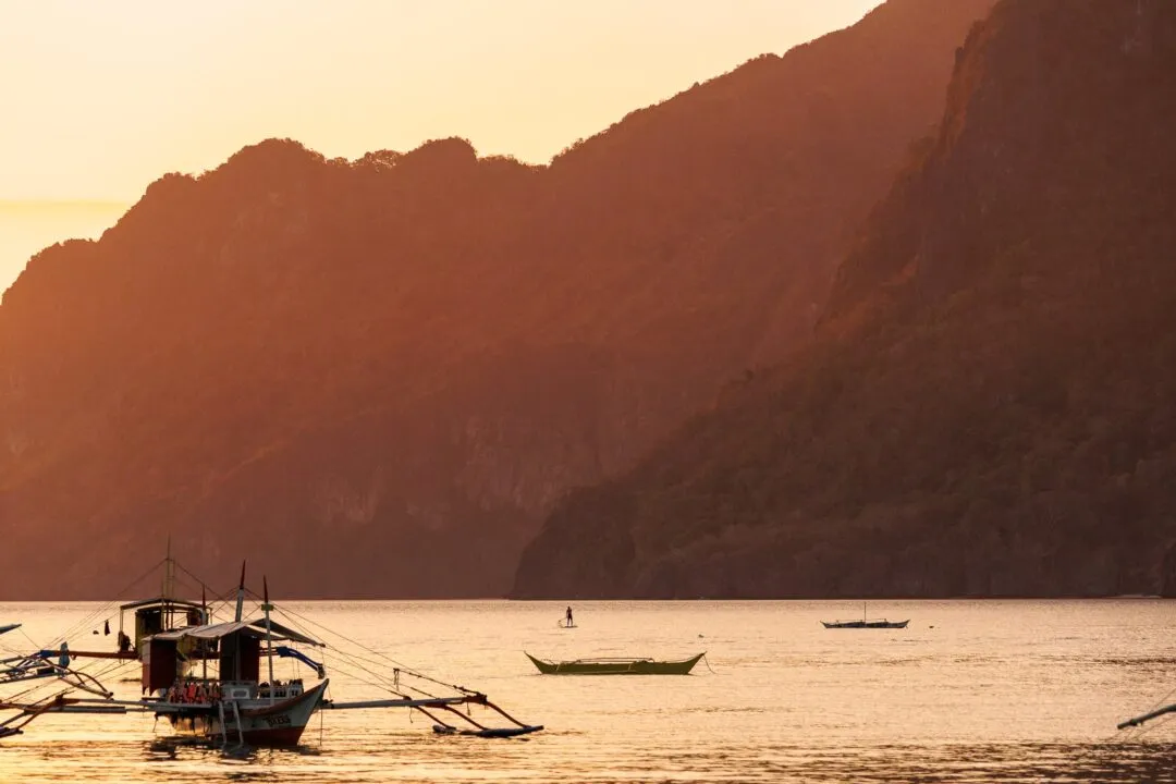 Paddleboarder loaded tour boat sunset El Nido