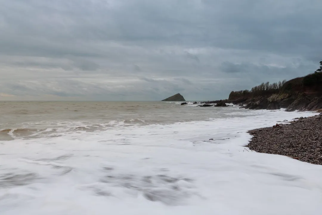 Foam-washed shoreline with Mew Stone in the distance, Wembury, Devon