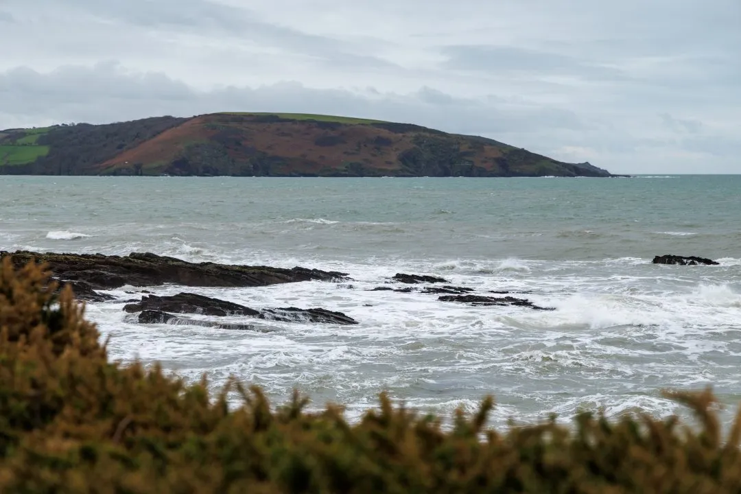 Rocky foreshore below green headland hills, Wembury, Devon