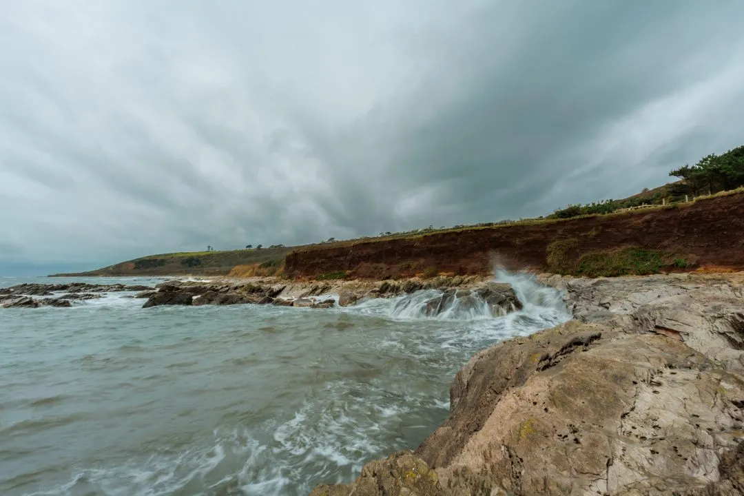 Wave splashing against a red cliff, Wembury, Devon