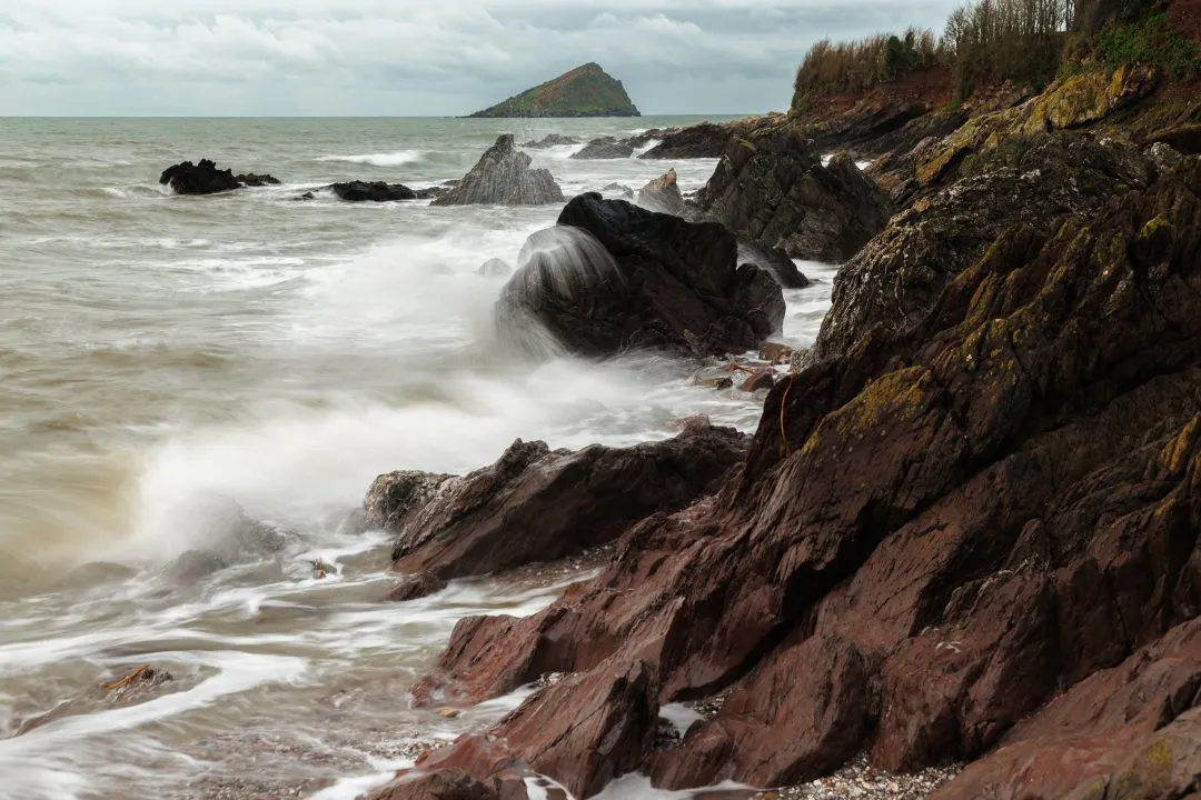 Wave splashing over rocks with Mew Stone behind, Wembury, Devon