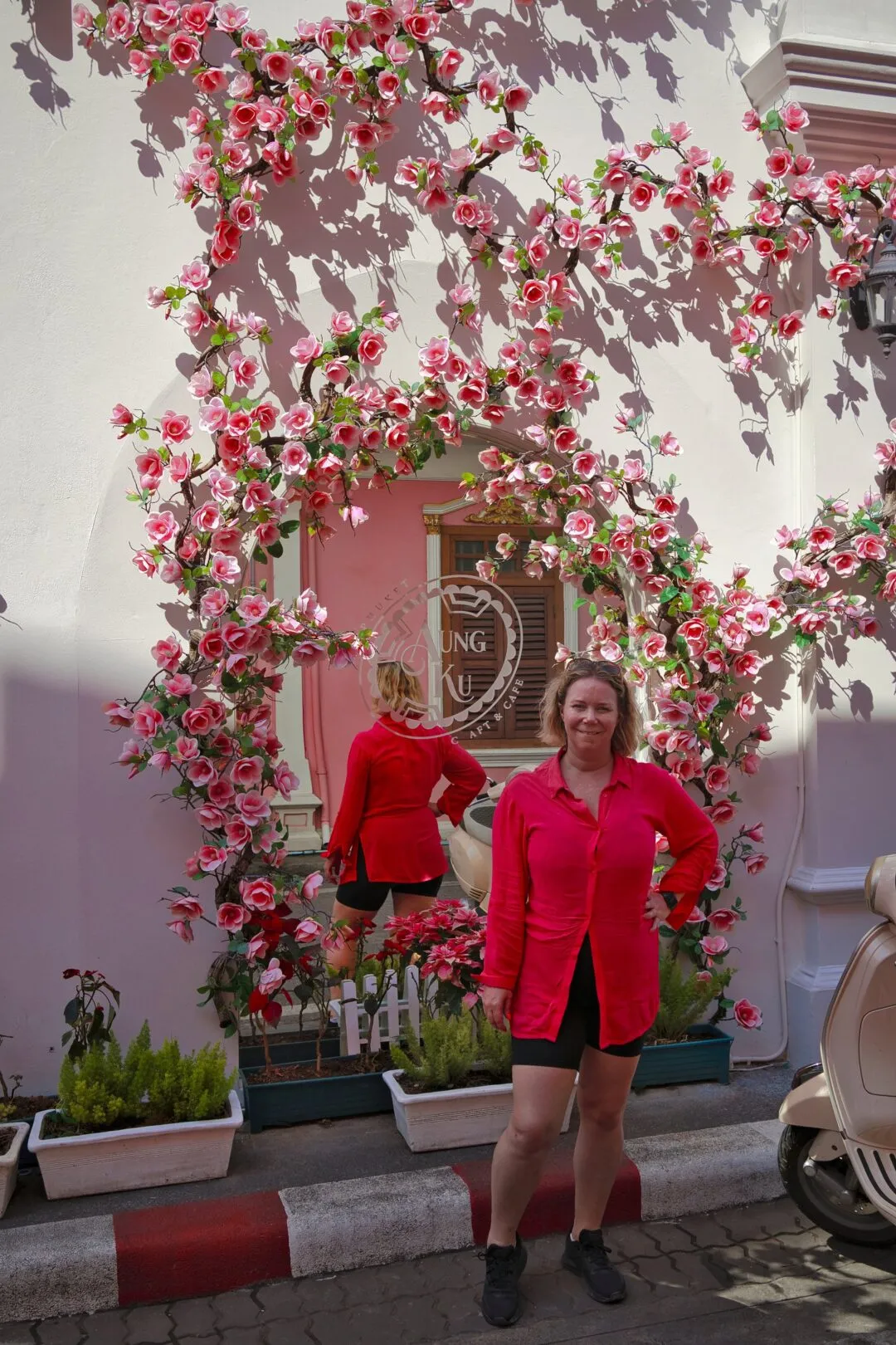 A portrait taken under a rose-covered archway in Phuket Old Town, Thailand.